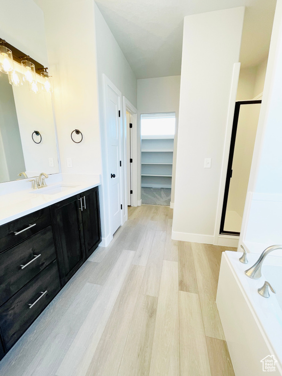 Full bathroom with a stall shower, wood finished floors, vanity, and a bath