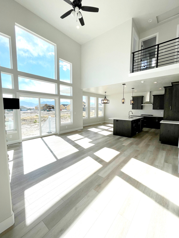 Living room with a towering ceiling, ceiling fan, and light wood-type flooring