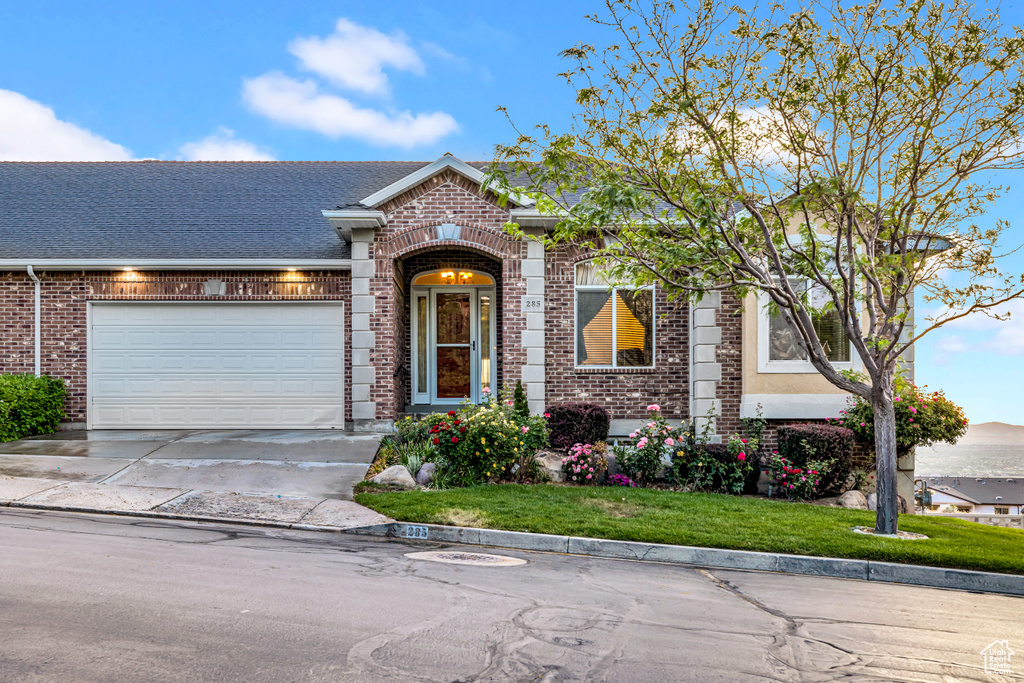 View of front of home featuring brick siding, concrete driveway, a garage, and a front yard