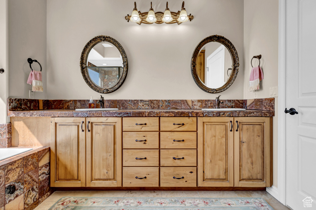 Full bath featuring double vanity, tile patterned floors, and tiled tub