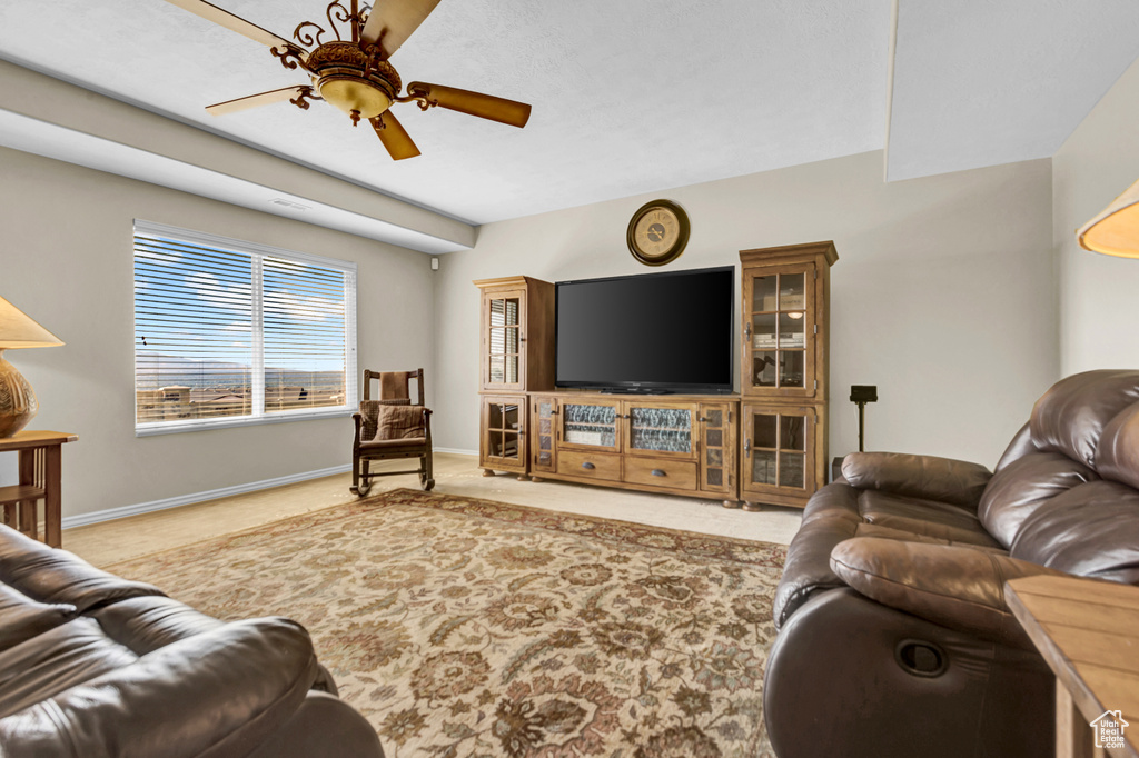 Carpeted living room featuring ceiling fan and baseboards