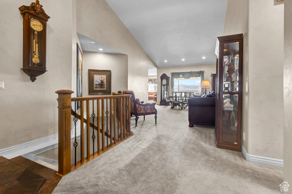 Hallway with an upstairs landing, lofted ceiling, recessed lighting, and carpet flooring