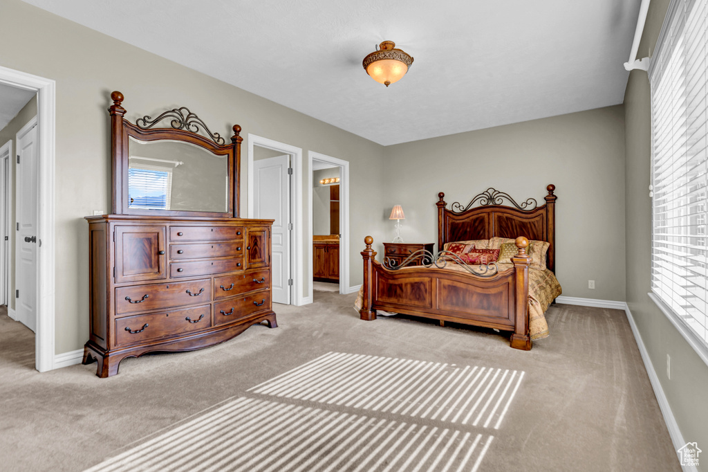 Bedroom featuring light carpet, multiple windows, and connected bathroom