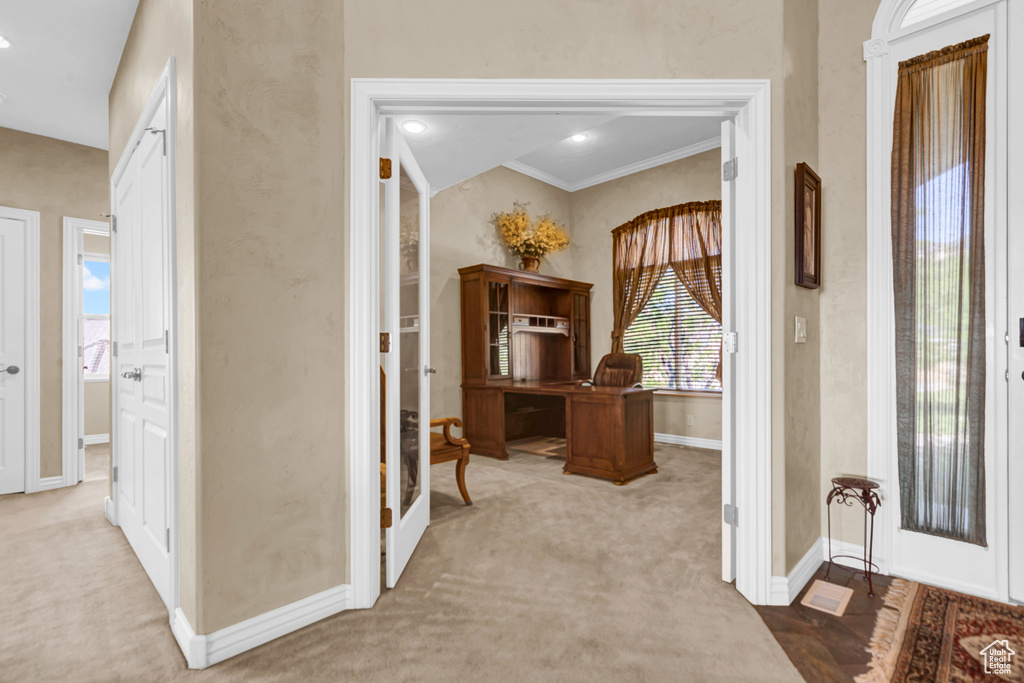 Carpeted entrance foyer featuring baseboards and crown molding