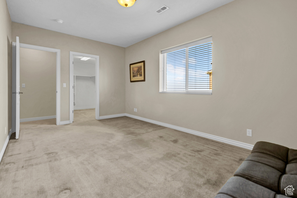 Unfurnished bedroom with a spacious closet and carpet