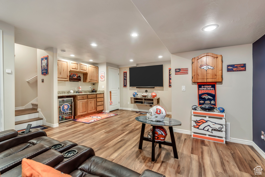 Living area featuring beverage cooler, bar, light wood-style floors, recessed lighting, and stairway