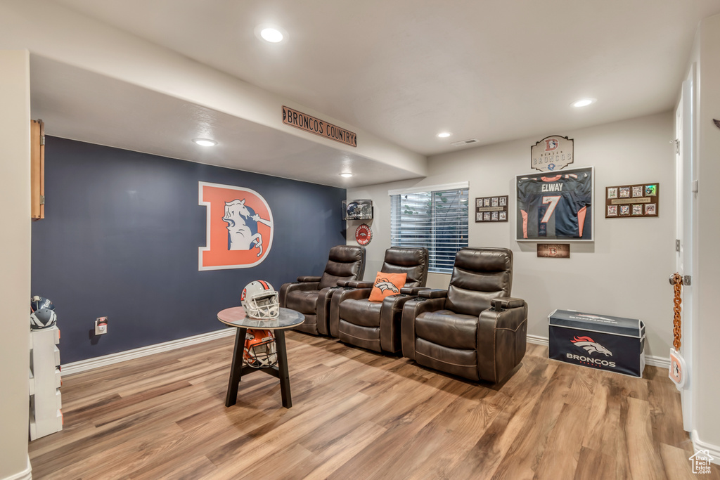 Home theater room with light wood finished floors and recessed lighting