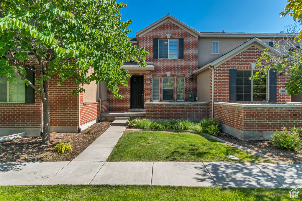Traditional-style home with brick siding, a front yard, and stucco siding
