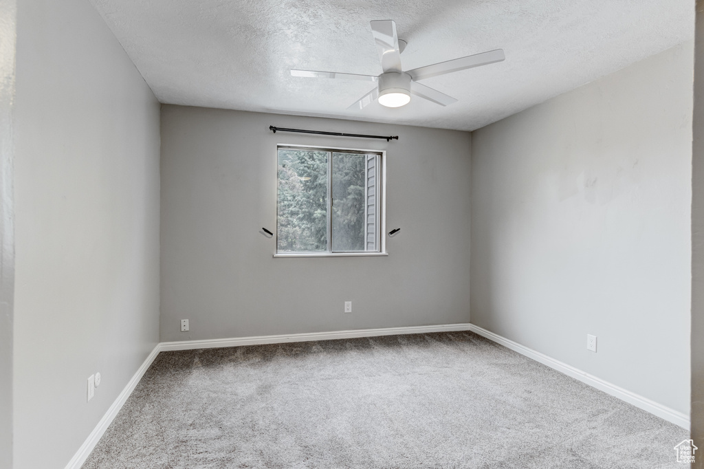 Spare room featuring a textured ceiling, carpet floors, and a ceiling fan