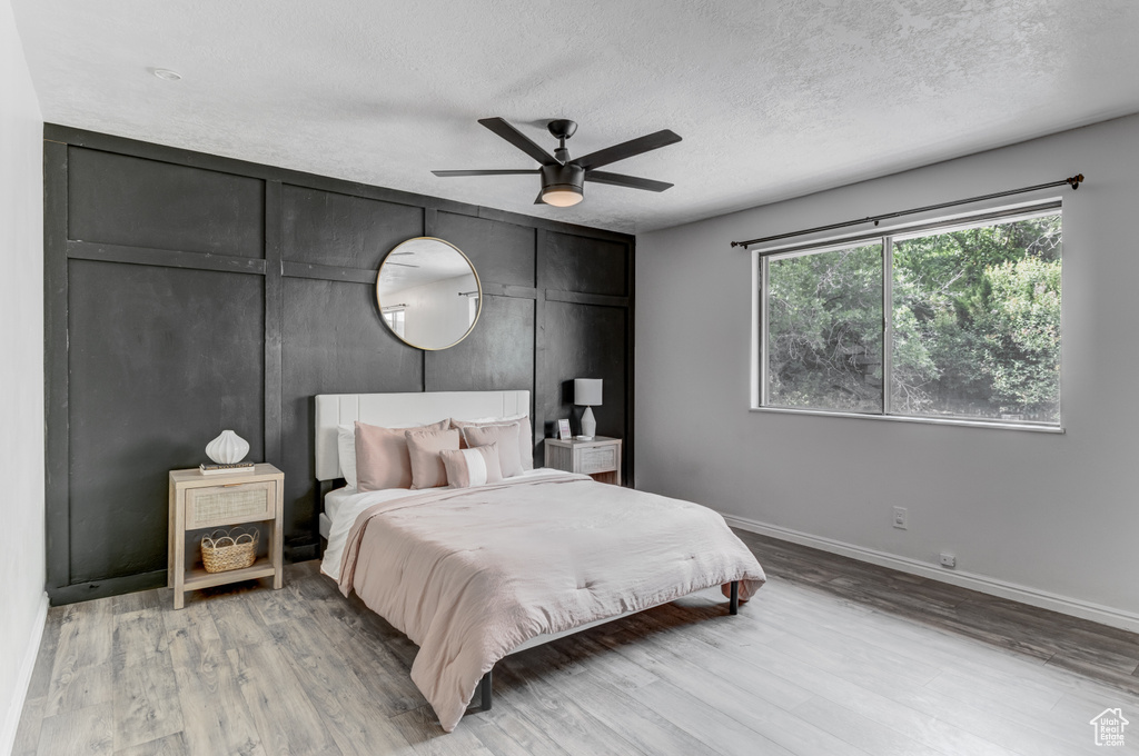 Bedroom with light wood finished floors, a textured ceiling, and ceiling fan