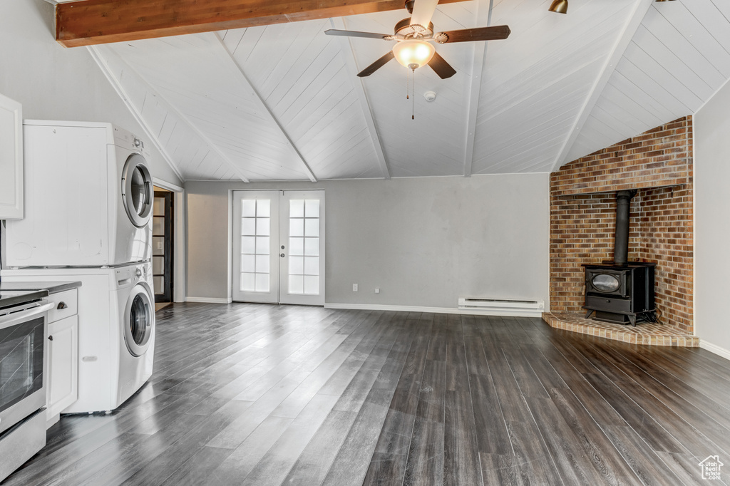 Unfurnished living room with stacked washer / dryer, a ceiling fan, dark wood-style floors, baseboard heating, and wood ceiling