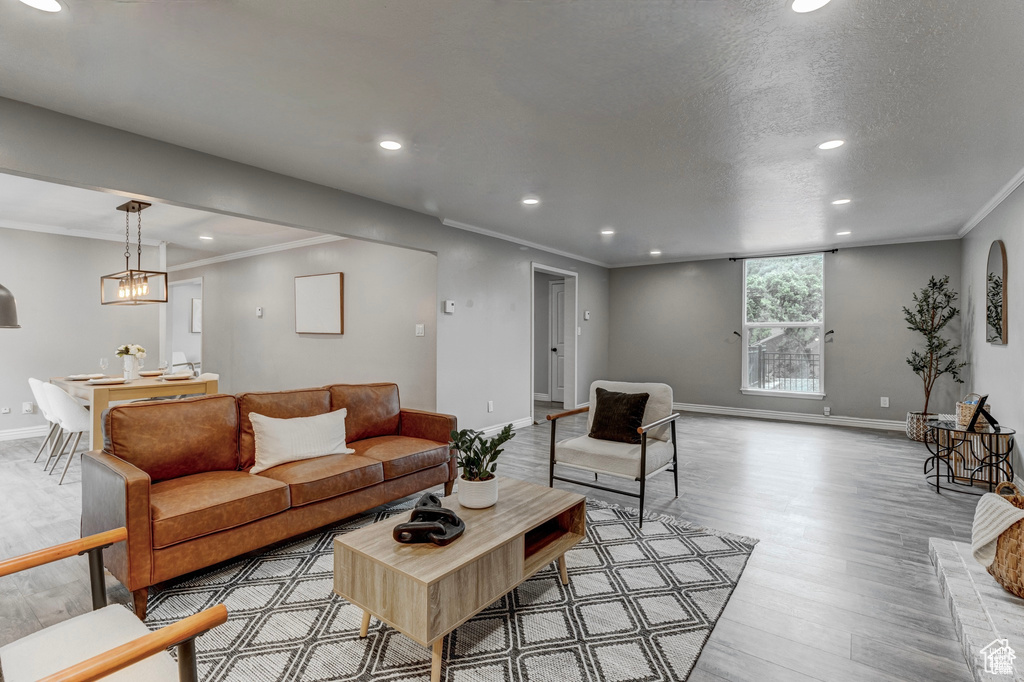 Living area with wood finished floors, recessed lighting, and ornamental molding