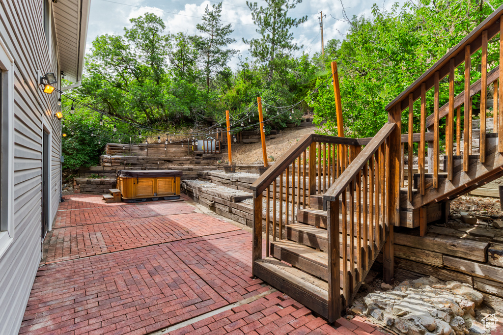 Wooden deck with stairs, a hot tub, and a patio area