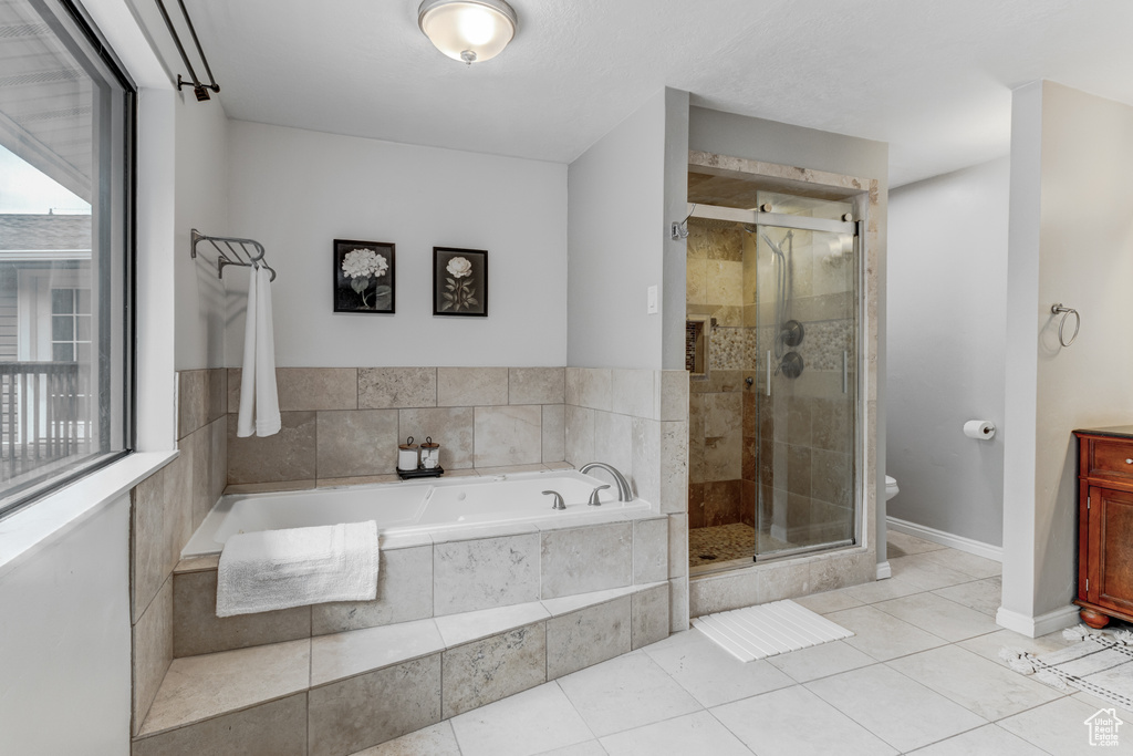 Bathroom featuring a bath, a stall shower, tile patterned floors, and vanity
