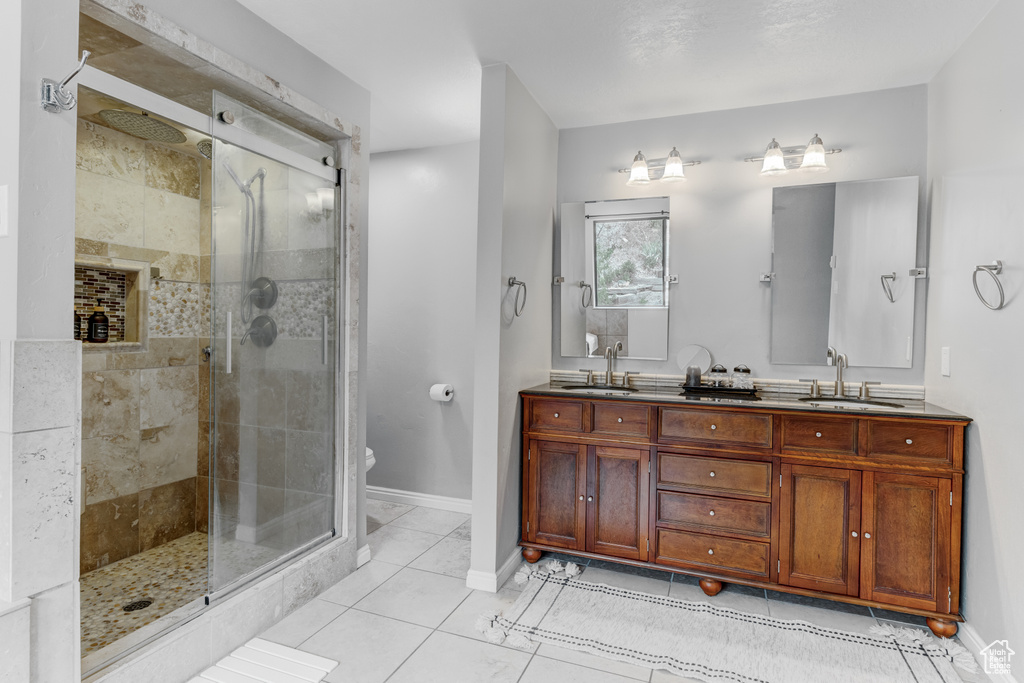 Full bath featuring a shower stall, double vanity, and tile patterned flooring