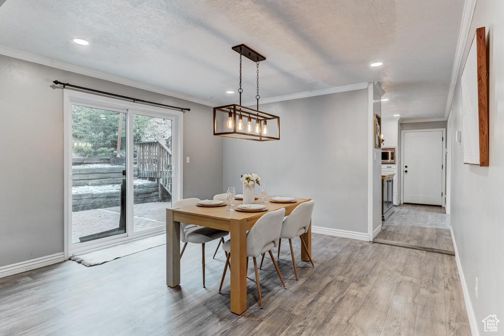 Dining area with light wood-style flooring, recessed lighting, and crown molding