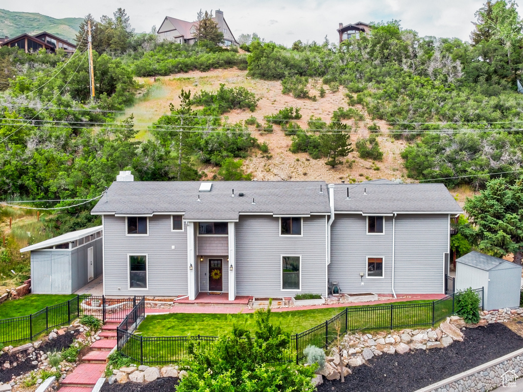 View of front of home featuring a storage unit and a fenced backyard