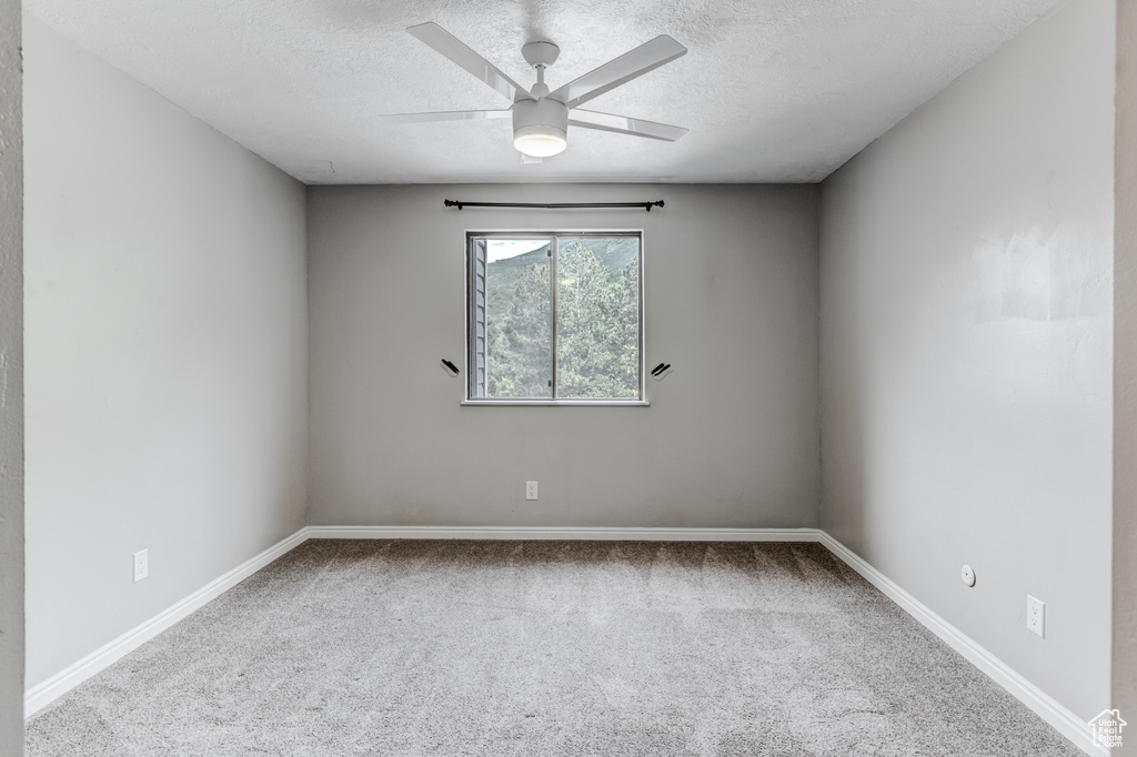 Carpeted spare room with ceiling fan and a textured ceiling