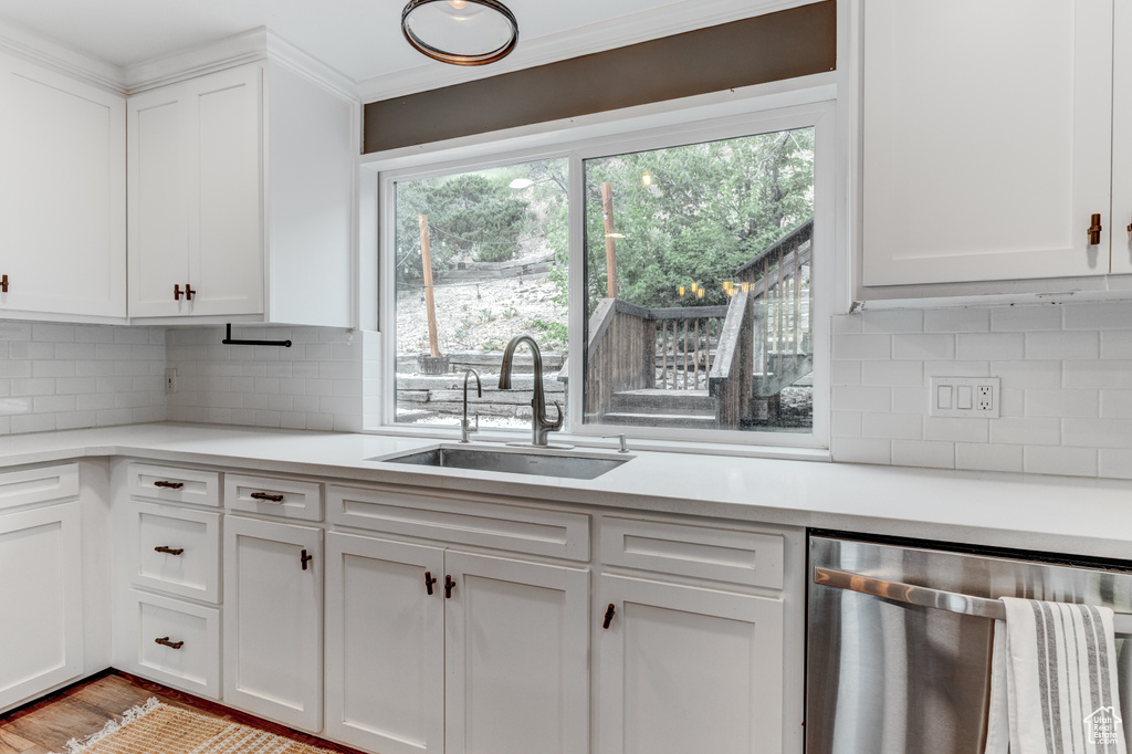 Kitchen featuring dishwasher, light countertops, white cabinets, and crown molding