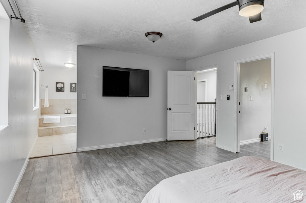 Bedroom with wood finished floors, a textured ceiling, ensuite bath, and ceiling fan