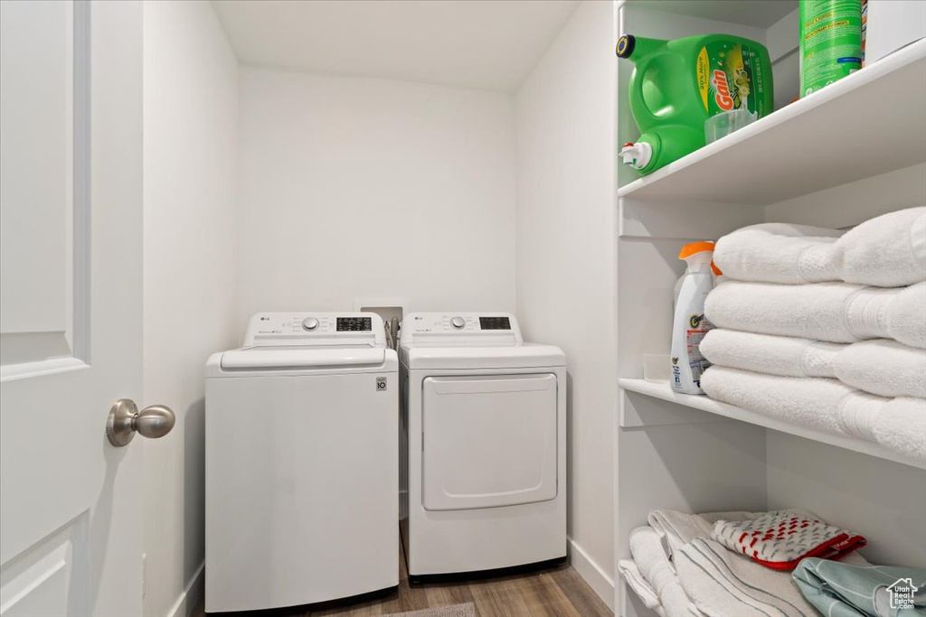 Washroom with washing machine and clothes dryer and wood finished floors