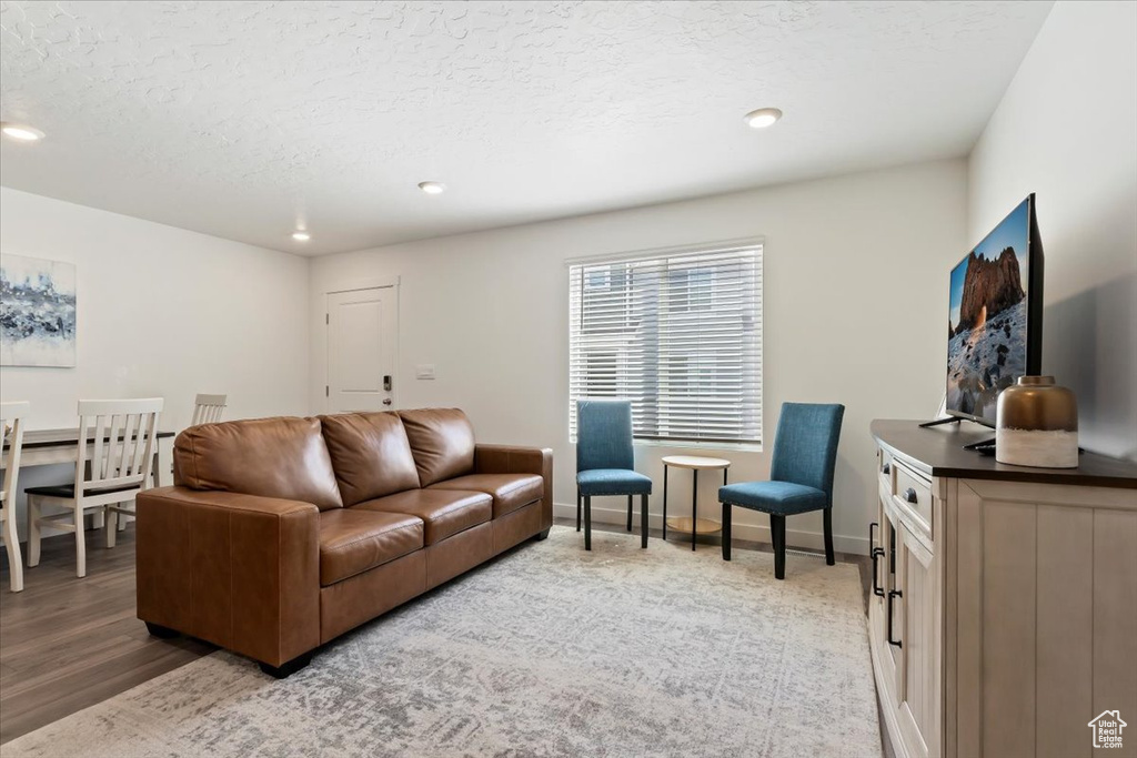 Living room with recessed lighting, a textured ceiling, and light wood-style floors