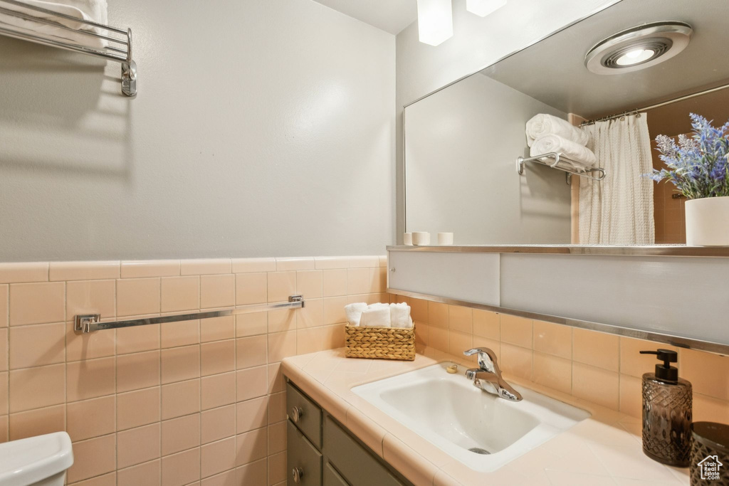 Full bathroom with vanity, tile walls, a wainscoted wall, and curtained shower
