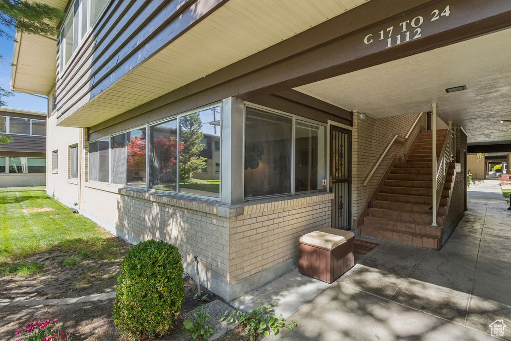 View of side of property featuring brick siding, stairway, and a patio