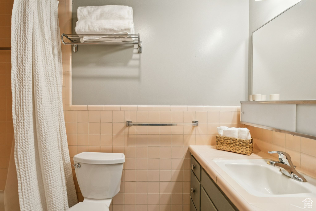 Full bathroom with tile walls, vanity, and a wainscoted wall