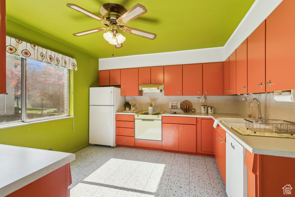 Kitchen with white appliances, under cabinet range hood, ceiling fan, light countertops, and light floors