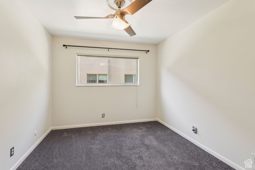 Carpeted empty room with ceiling fan and baseboards