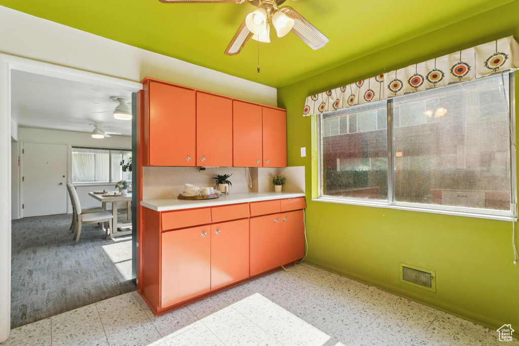 Kitchen with ceiling fan, red cabinetry, and healthy amount of natural light