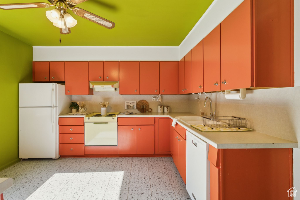 Kitchen with white appliances, a ceiling fan, light countertops, under cabinet range hood, and light flooring