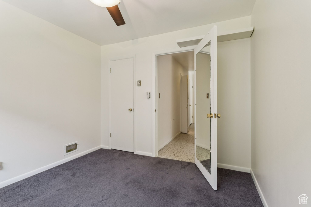 Carpeted empty room featuring ceiling fan and baseboards