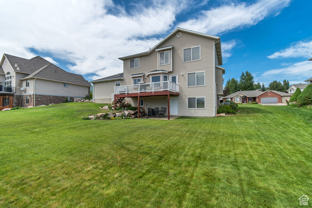 Back of house featuring a lawn, a deck, and a patio