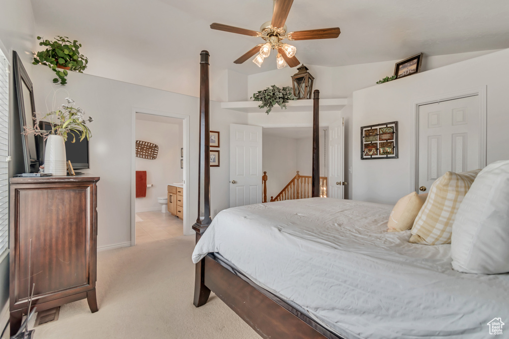 Bedroom with light colored carpet, lofted ceiling, connected bathroom, and ceiling fan
