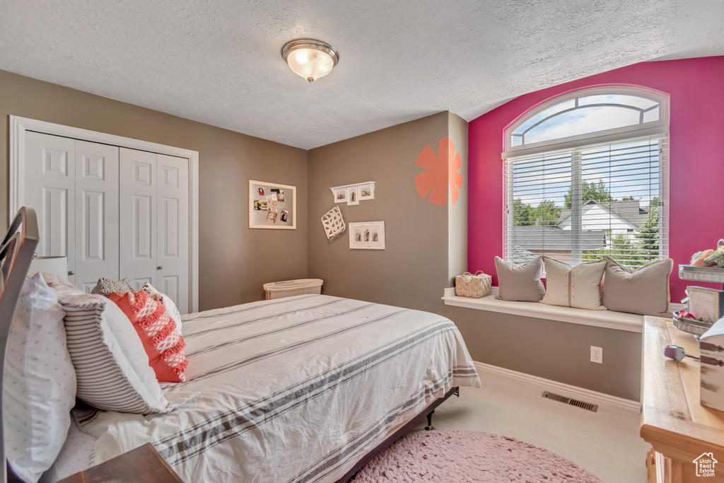 Bedroom with a textured ceiling, a closet, and carpet flooring