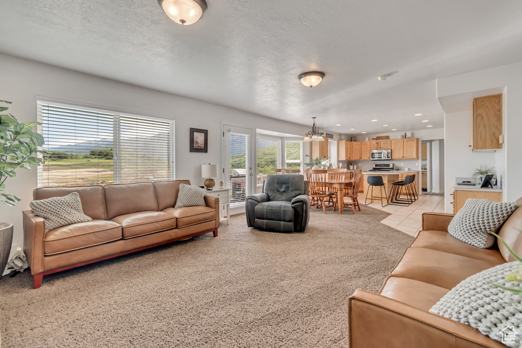 Living area with light colored carpet, a chandelier, and recessed lighting