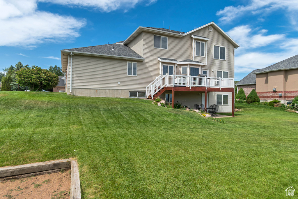 Back of house featuring a wooden deck, a yard, and stairs
