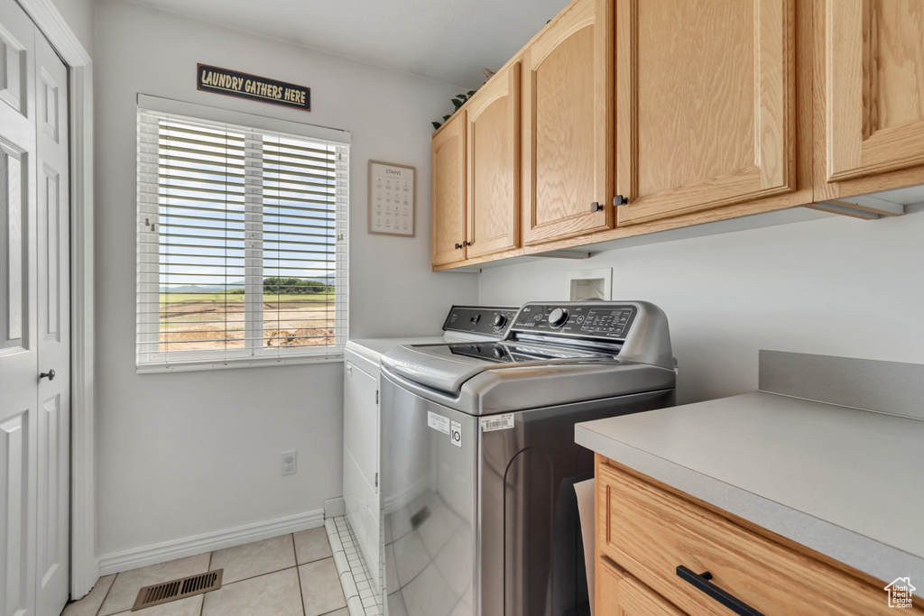 Laundry area featuring cabinet space, washing machine and clothes dryer, and light tile patterned floors