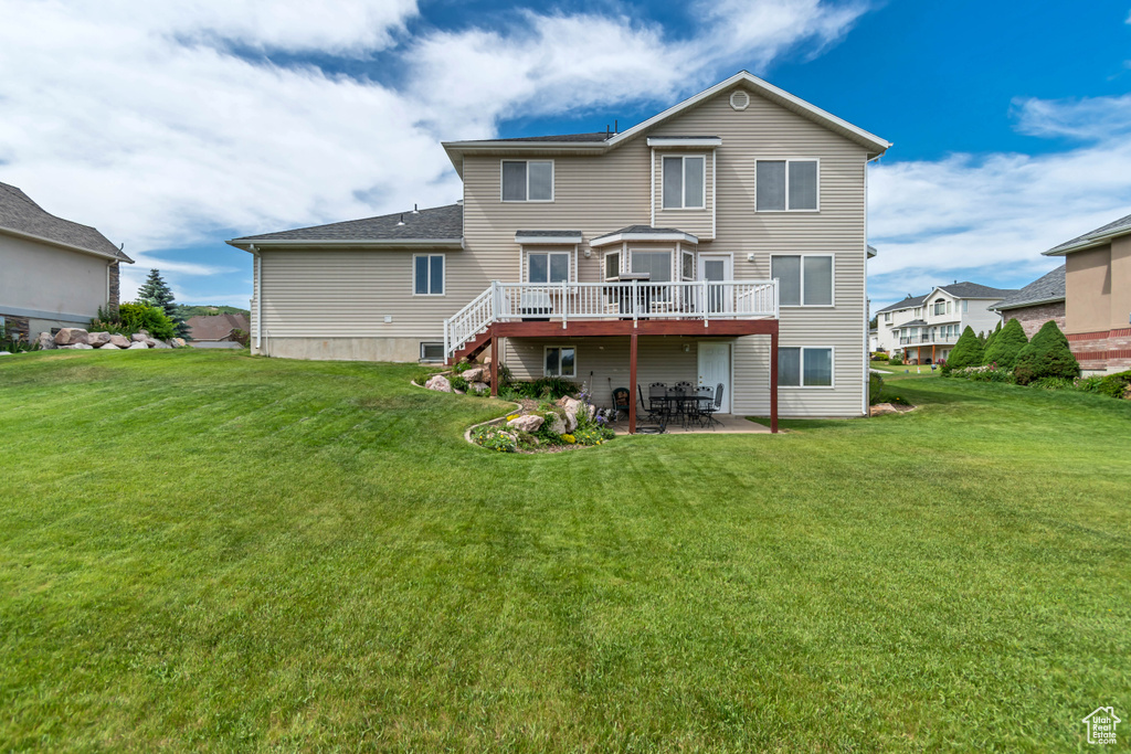 Rear view of house featuring a deck, a patio, a yard, and stairs