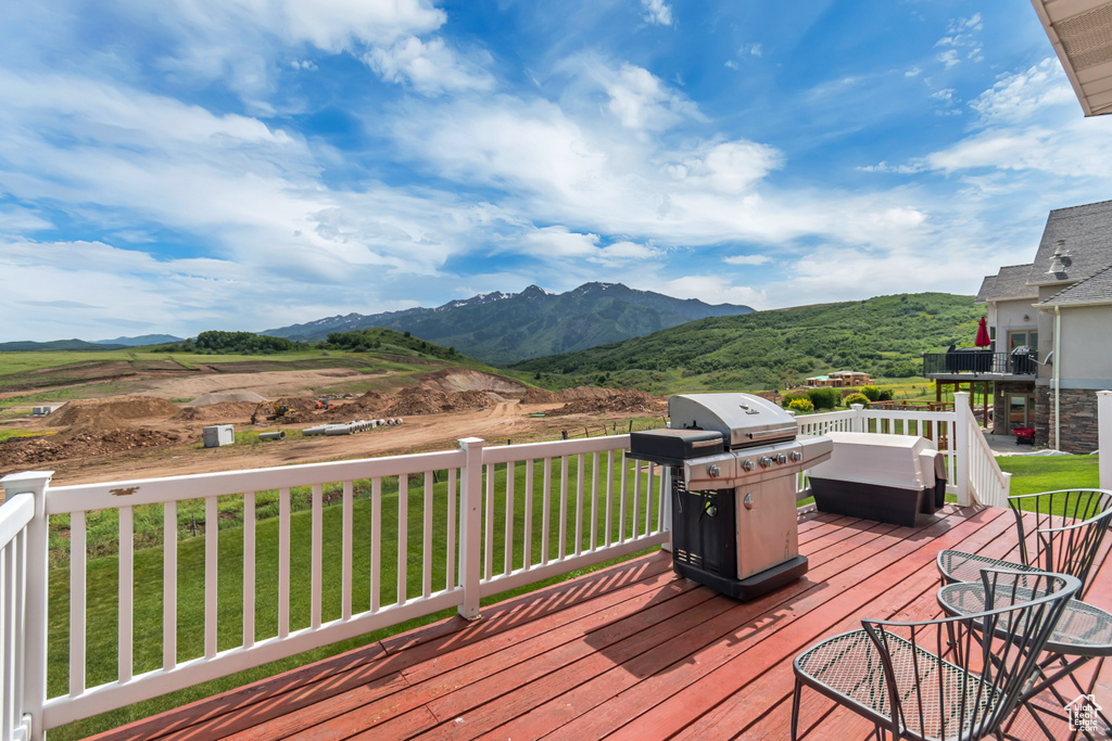 Deck with a grill, a mountain view, and a yard