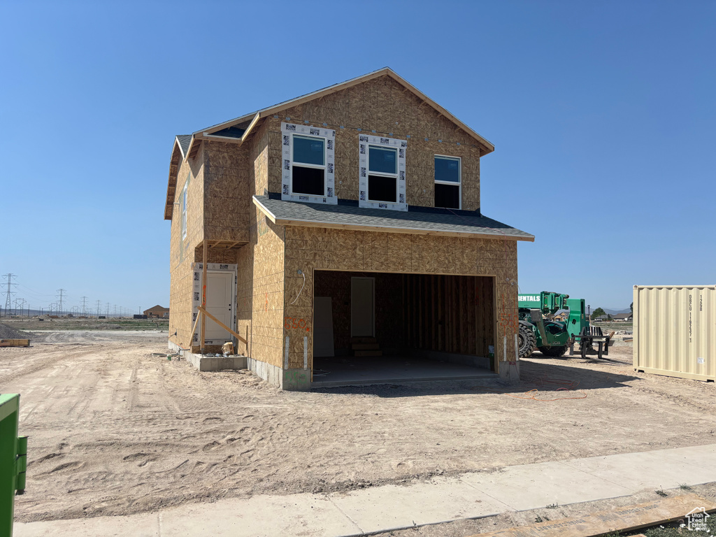 View of front of property featuring dirt driveway and a garage
