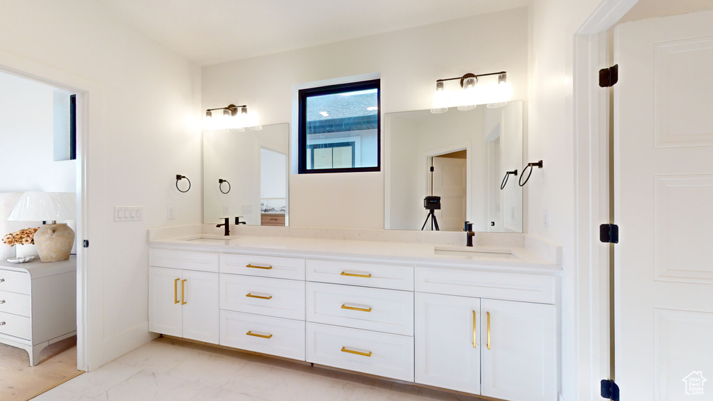 Bathroom with double vanity and marble finish flooring