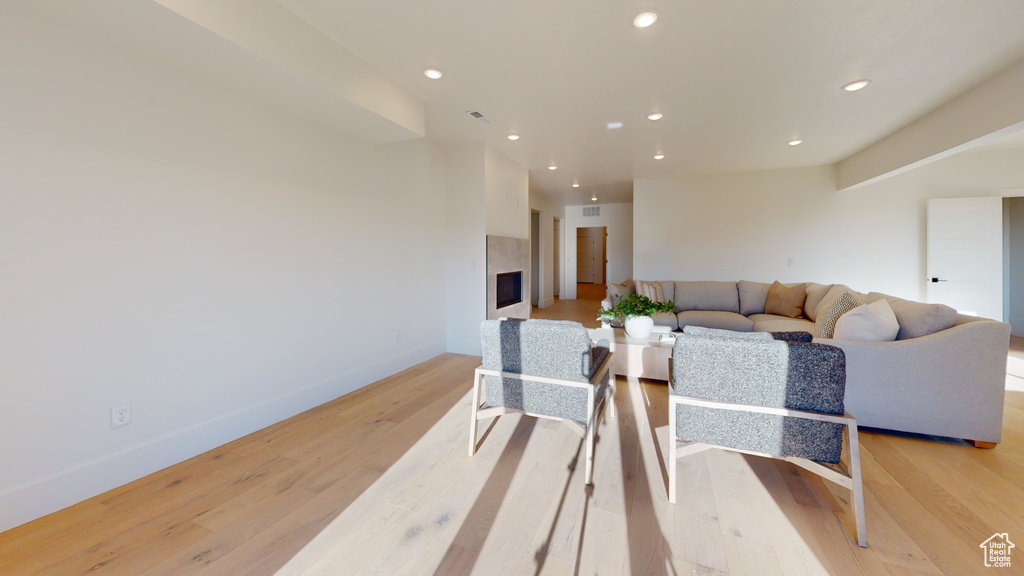 Living room with recessed lighting, light wood-type flooring, and a premium fireplace