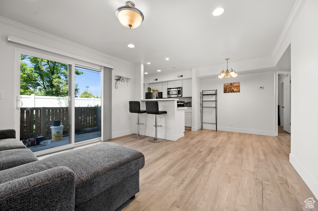Living area featuring ornamental molding, light wood finished floors, a chandelier, and recessed lighting