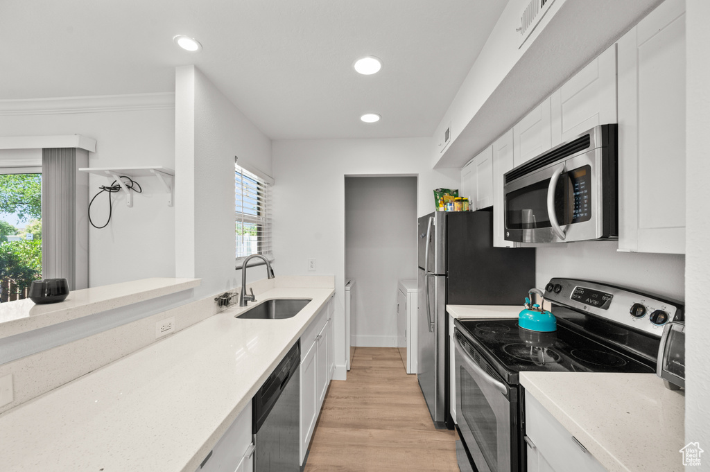 Kitchen with stainless steel appliances, white cabinets, light wood finished floors, plenty of natural light, and recessed lighting