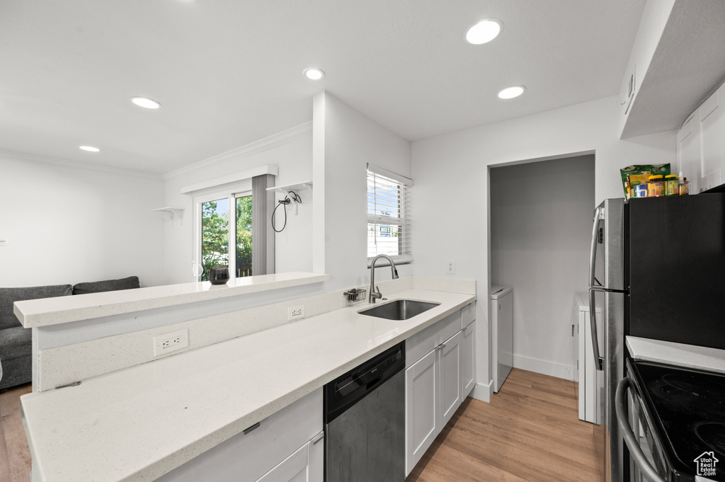 Kitchen with stainless steel appliances, recessed lighting, light wood-type flooring, white cabinets, and ornamental molding