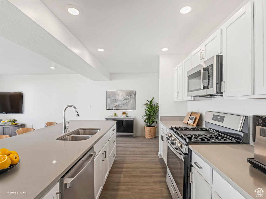Kitchen featuring stainless steel appliances, dark wood-style flooring, white cabinetry, recessed lighting, and light countertops