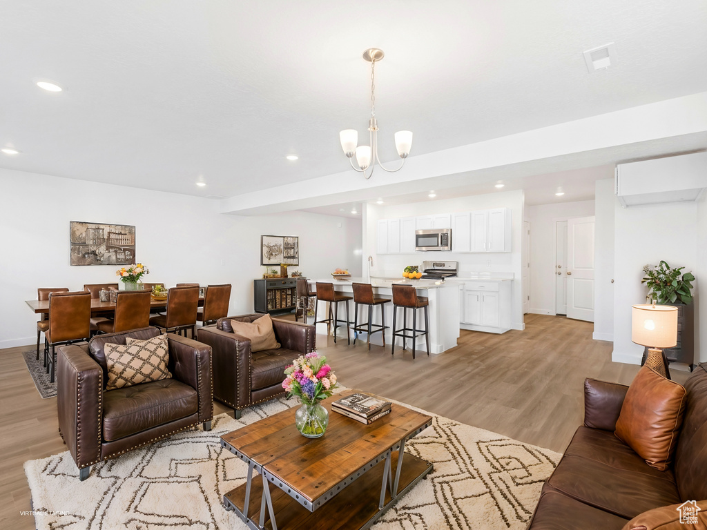 Living room with light wood-style flooring, recessed lighting, and a chandelier